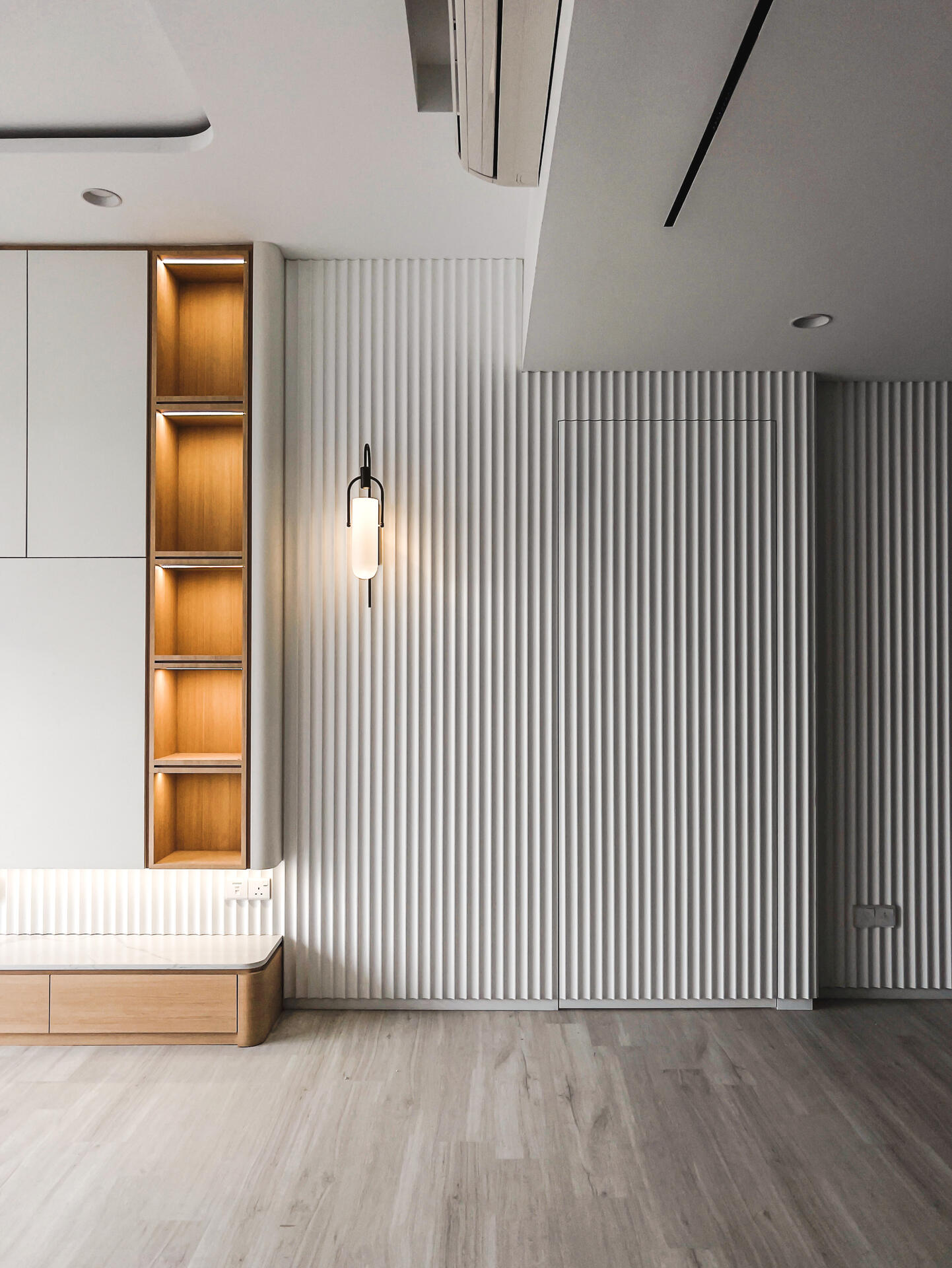 Modern minimalist interior with fluted paneling, open hidden door, and integrated storage shelves at Ativo Suites