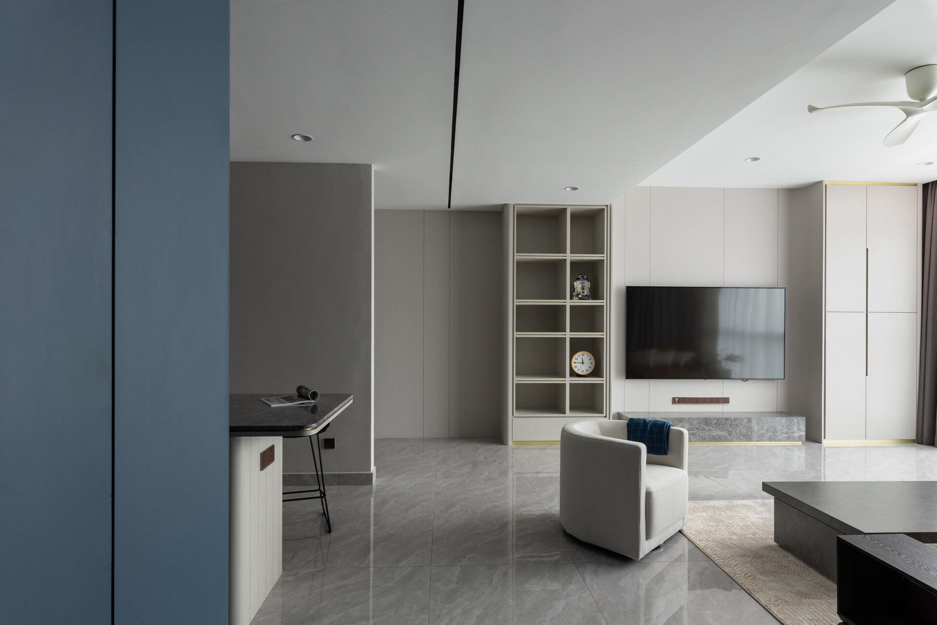 Contemporary living room with wall-mounted TV, custom shelving, and natural lighting at Uptown Residences